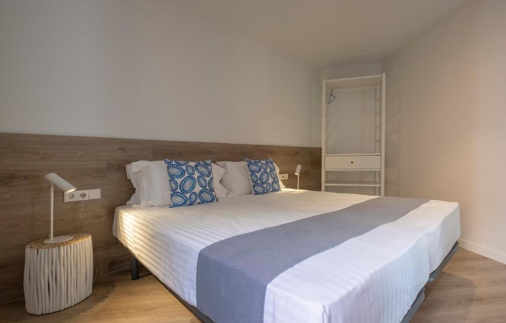 普拉加德阿罗Cliper Apartments by Escampa Hotels的卧室配有带蓝色枕头的大型白色床