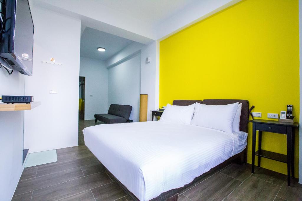 宜兰市山啄木青年旅馆的卧室配有白色的床和黄色的墙壁