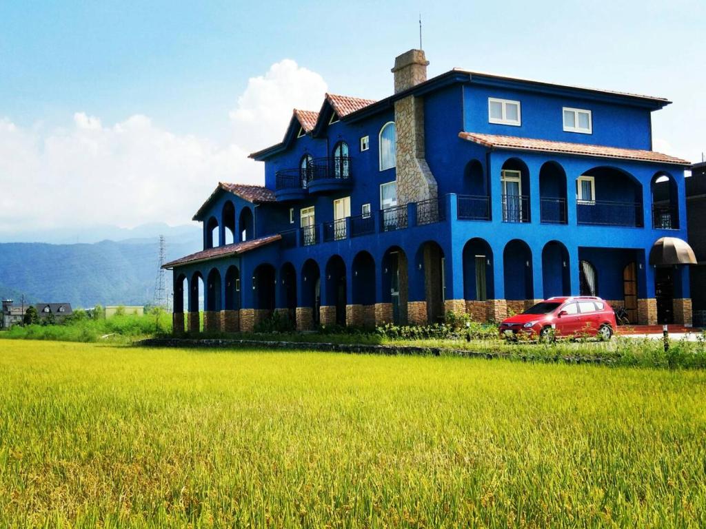 冬山乡Fly Inn 飛旅宿的蓝色的房子,前面有一辆红色的汽车