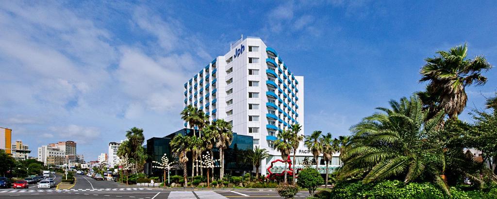济州市济州岛太平洋酒店的一座高大的白色建筑,种植了棕榈树,街道上