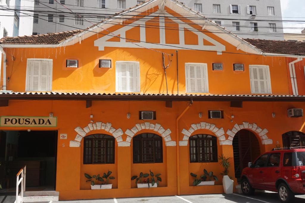 桑托斯Pousada Orquidário的一座橙色的建筑,前面有一辆红色的汽车