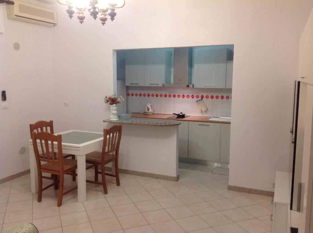 吉诺萨滨海Appartamento al mare Puglia的厨房配有桌子、两把椅子和一张桌子