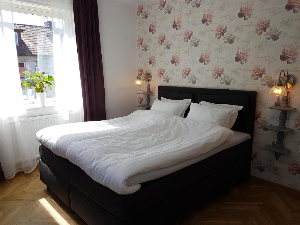 SmålandsstenarSmålandsstenar hotell的一间卧室配有一张带白色床单的床和一扇窗户。
