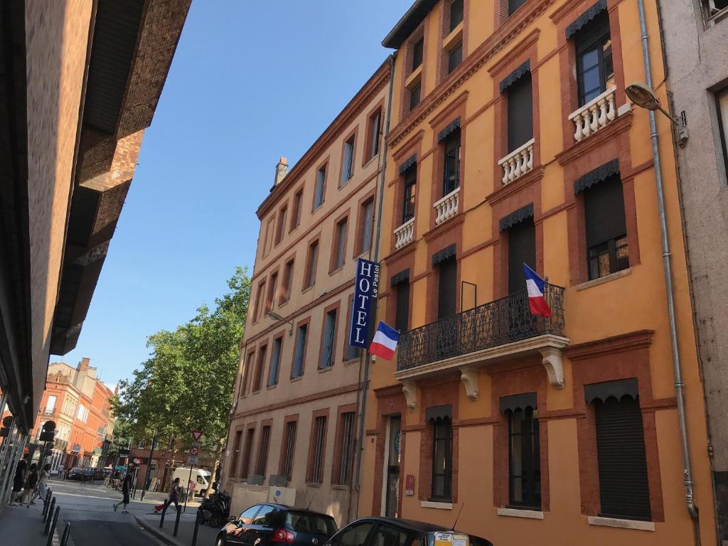图卢兹帕斯特尔酒店的街上的一座建筑,上面有两面旗帜