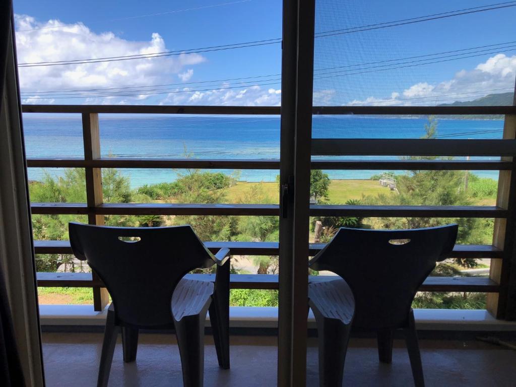 奄美Guest room Halemakana的两把椅子,在窗户前,眺望着大海