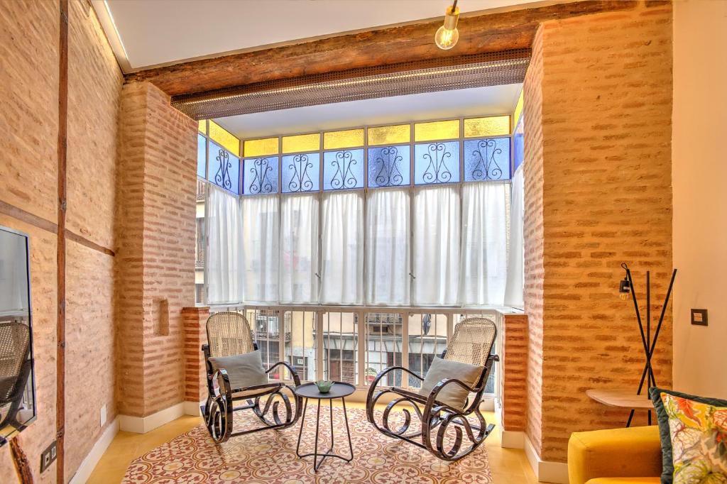 托莱多Casa Meninas y Anillo Apartamentos Deluxe MeninasCollection的客厅配有椅子、桌子和窗户