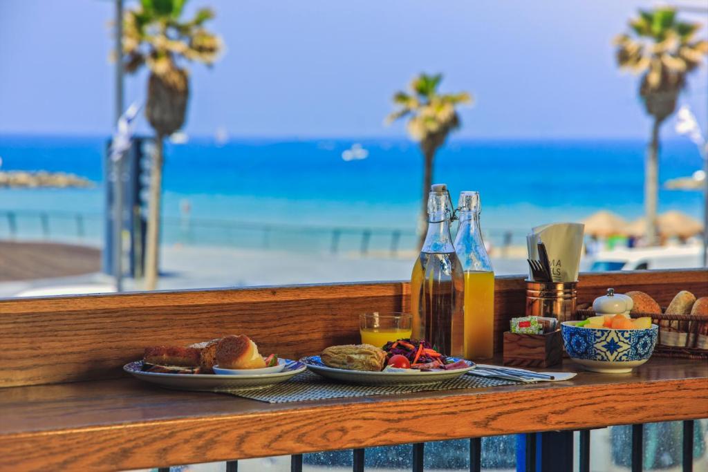 特拉维夫普里曼特拉维夫酒店的一张桌子,上面放着食物和饮料盘,还有海滩