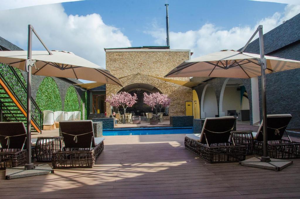 内罗毕贝斯特韦斯特PLUS子午线旅馆的一个带椅子和遮阳伞的甲板和一个游泳池