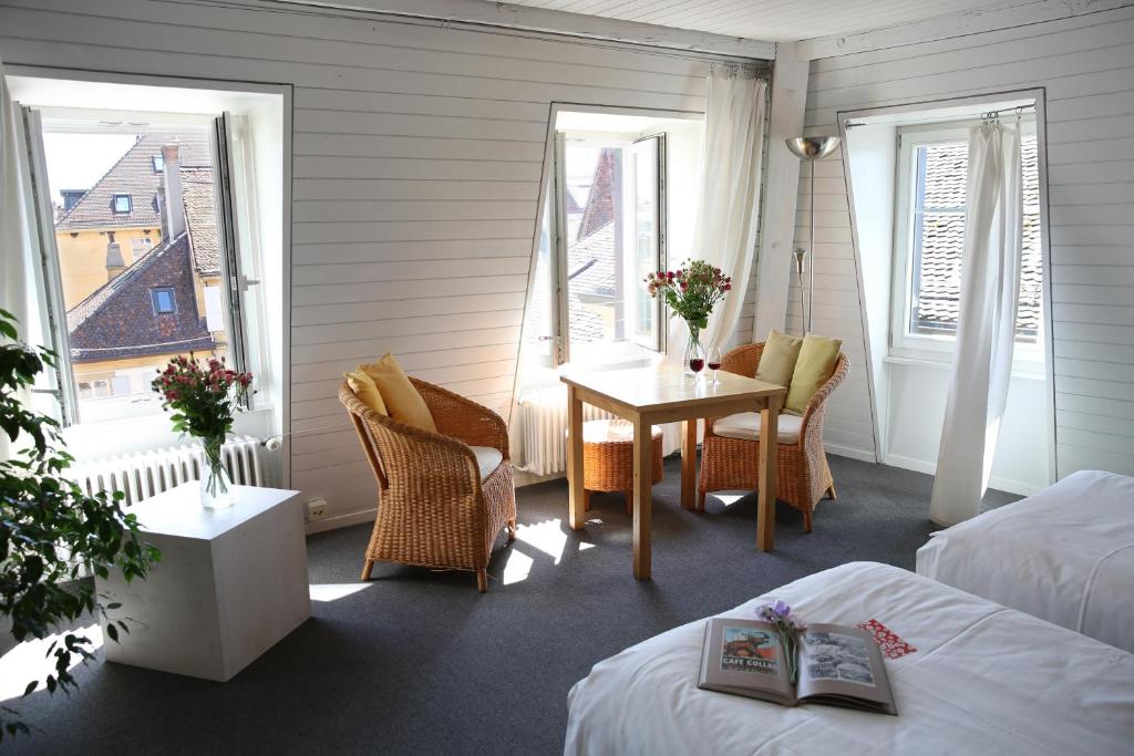 纳沙泰尔Le Café-Hôtel de L'Aubier的客房设有两张床、一张桌子和窗户。