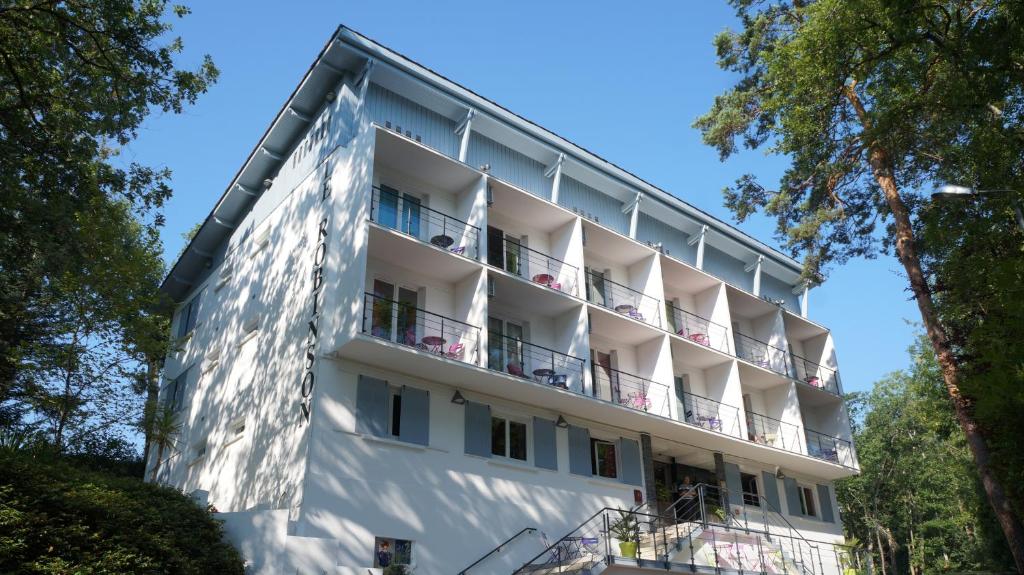 欧什罗宾逊酒店的带阳台和树木的白色公寓大楼