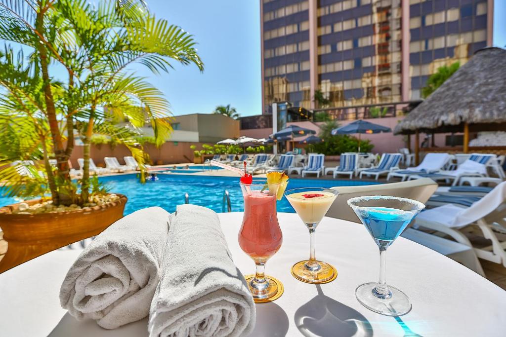 戈亚尼亚卡斯特罗公园酒店的一张在泳池边的白色桌子上喝着饮料