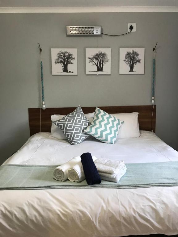 博克斯堡Celtis Lane Guest House的一张带两条毛巾和三张照片的床