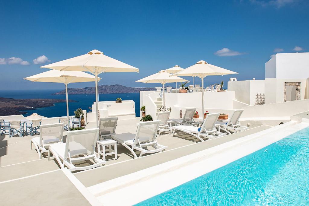 费拉潘特里亚套房酒店的一个带白色椅子和遮阳伞的游泳池以及大海
