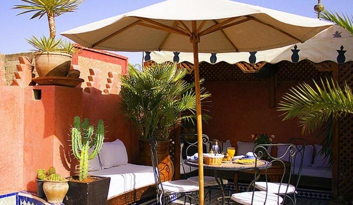 马拉喀什Riad Bab Chems的庭院配有遮阳伞和桌椅。