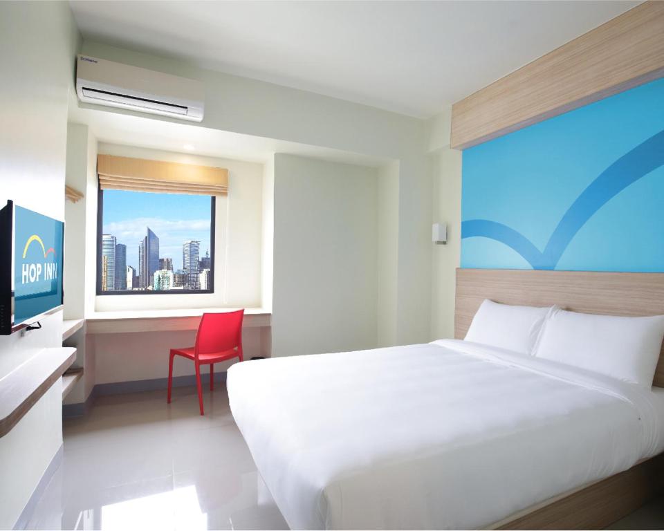 马尼拉Hop Inn Hotel Ermita Manila的一间卧室配有一张床、一张书桌和一个窗户。