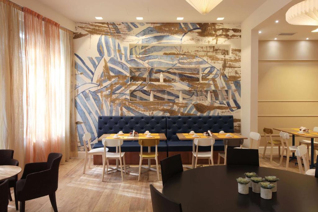贝加莫皮埃蒙特贝斯特韦斯特酒店的用餐室配有桌椅和壁画