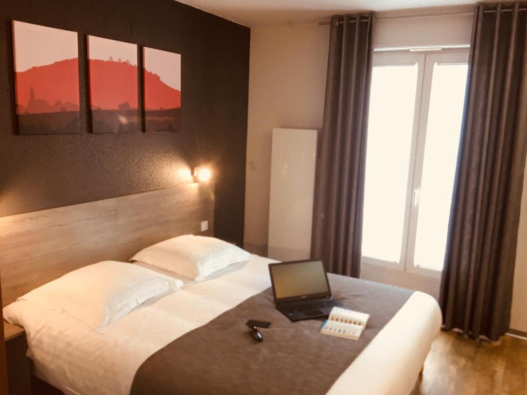 埃圭斯海姆Hotel Colmar Vignes Eguisheim的酒店客房,配有一张带笔记本电脑的床