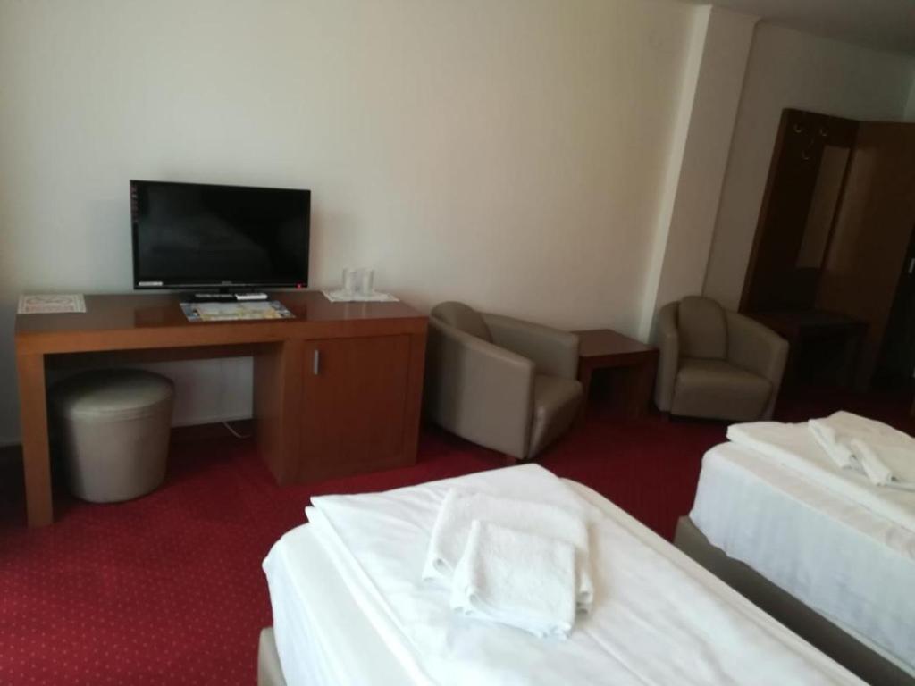 梅迪亚什Hotel Dennis的酒店客房设有两张床、一张桌子和一台电视。