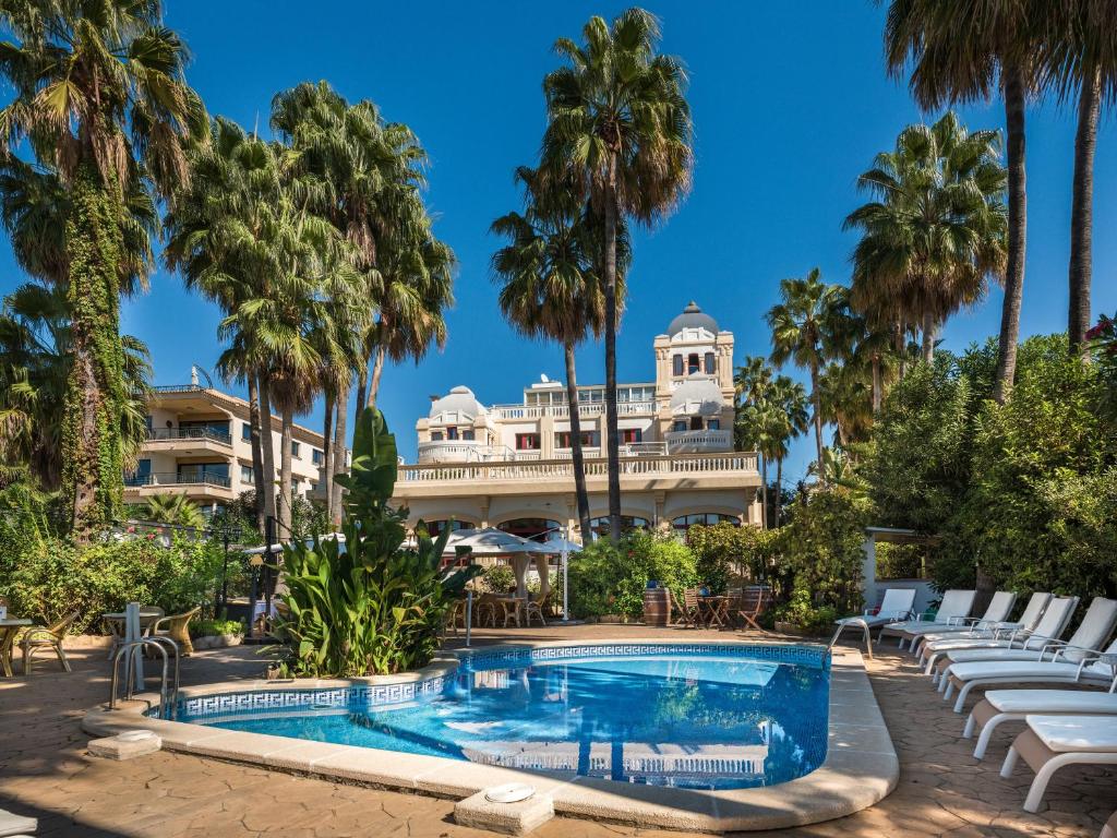 马略卡岛帕尔马哈迪城市酒店的一个带游泳池和棕榈树的度假村