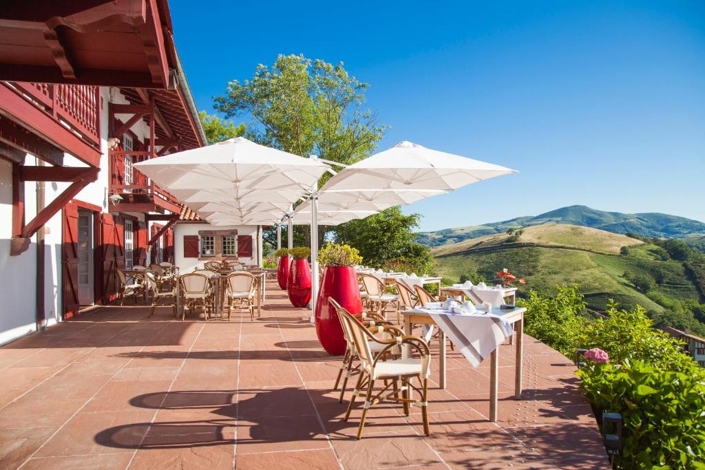 比达莱奥斯塔佩旅馆的一个带桌椅和白色遮阳伞的庭院。