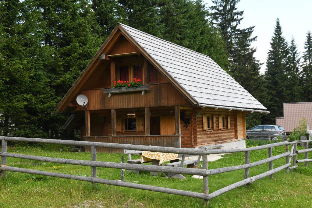 GoreljekPOČITNIŠKA HIŠA JURČEK POKLJUKA的一座带窗户和围栏的小木房子