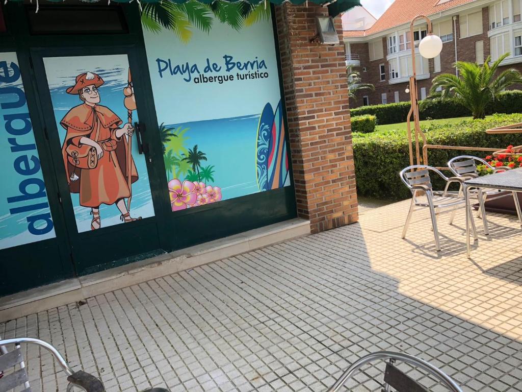 桑托尼亚Albergue Turistico Playa de Berria的门上标有桌椅的餐厅