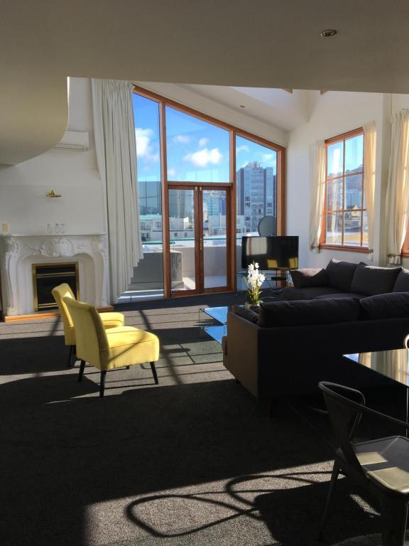 惠灵顿U Suites on Courtenay的客厅配有黑色沙发和黄色椅子