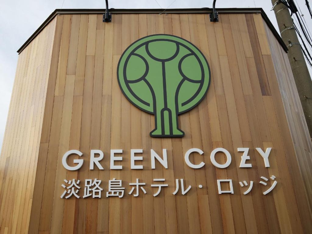 南淡路市Awajishima Hotel Lodge GREEN COZY的建筑物一侧的绿色软木标志
