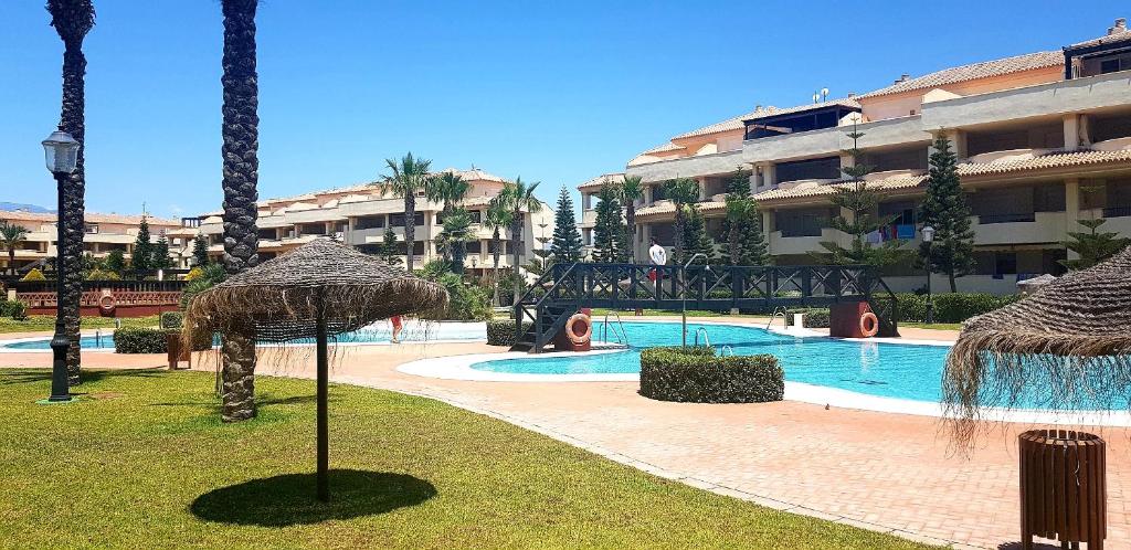 滨海罗克塔斯Apartamento Villa Romana Playa的一个带遮阳伞的游泳池的度假酒店