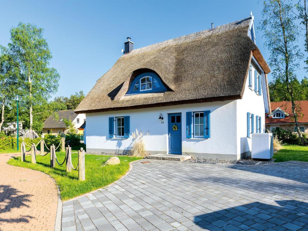 格洛韦Ferienhaus Auszeit - D 120.017的白色的房子,有茅草屋顶和车道