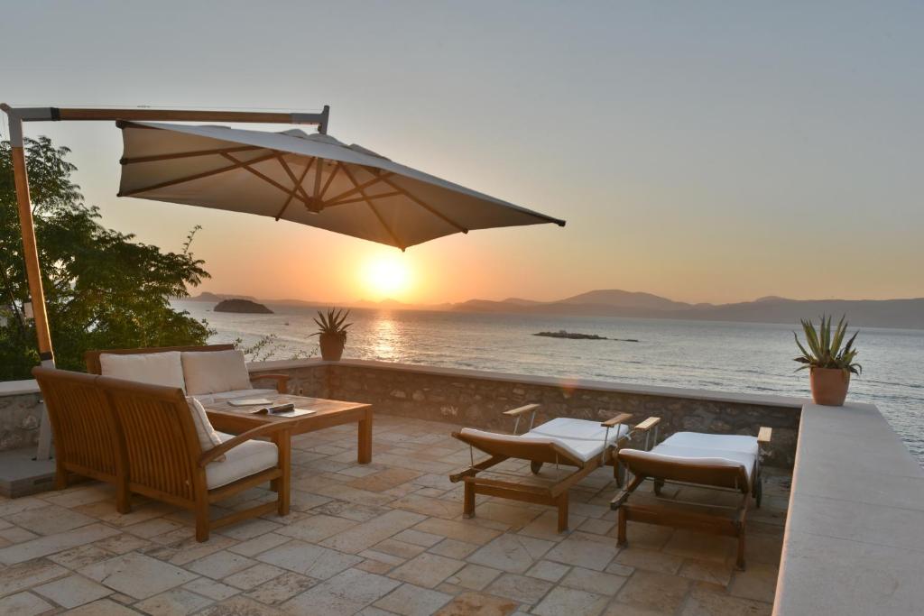 伊兹拉Hydra Kamini Beach Thea的庭院配有桌椅和遮阳伞。