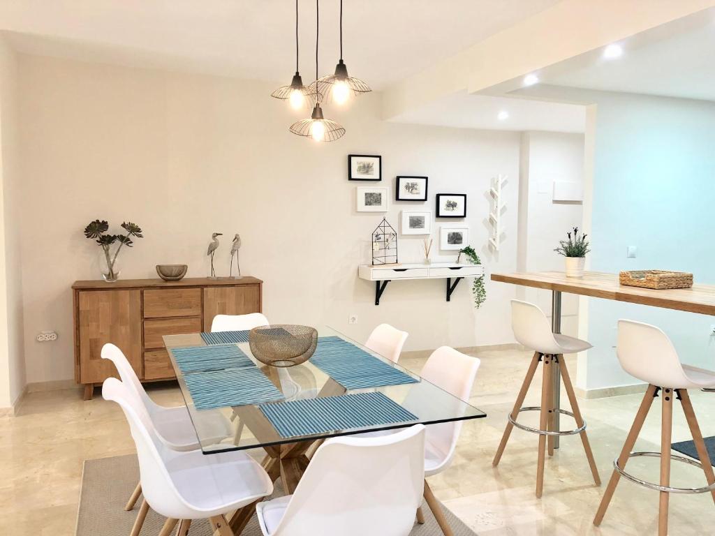 马贝拉Apartamento Guadalmina - Golf & Playa - Marbella的一间设有玻璃桌和白色椅子的用餐室