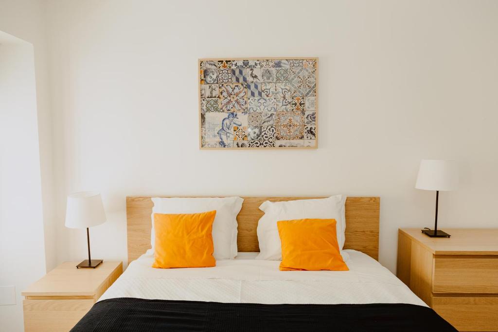 里斯本A Casa do Jardim à Estrela I的一间卧室配有带两个橙色枕头的床