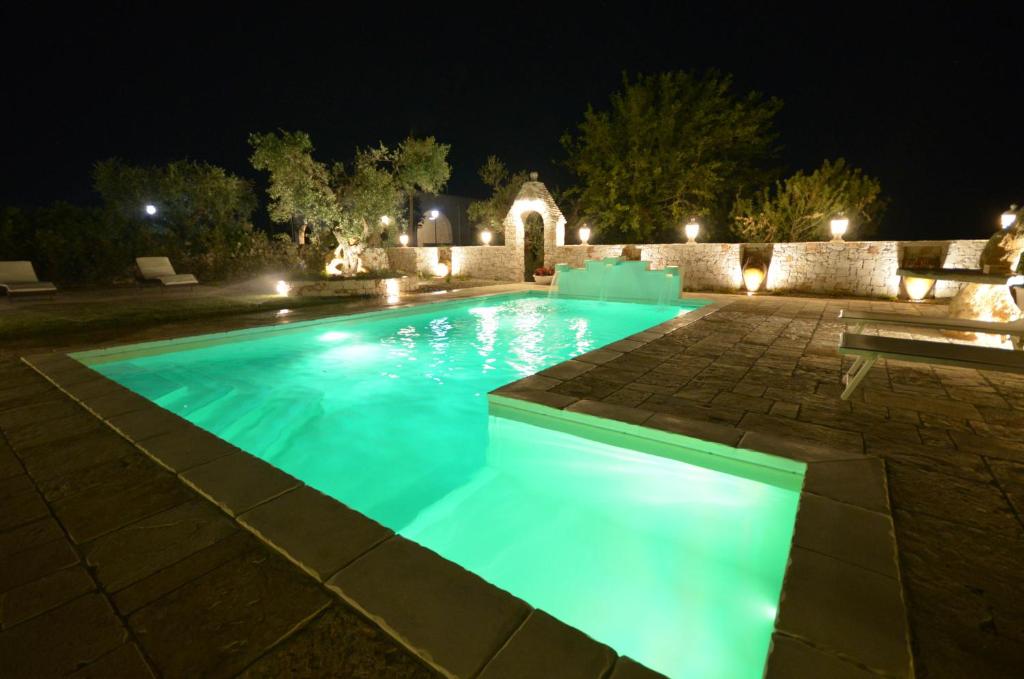 洛科罗通多Villa Petra Chiara的夜晚在院子里的游泳池里有一个蓝色的灯光
