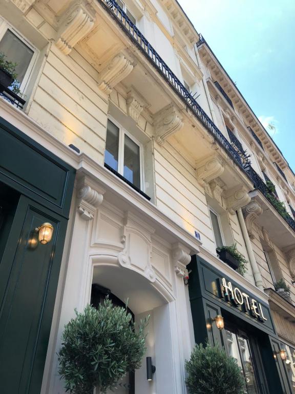 巴黎New Hotel Le Voltaire的门口有植物的建筑物前的商店