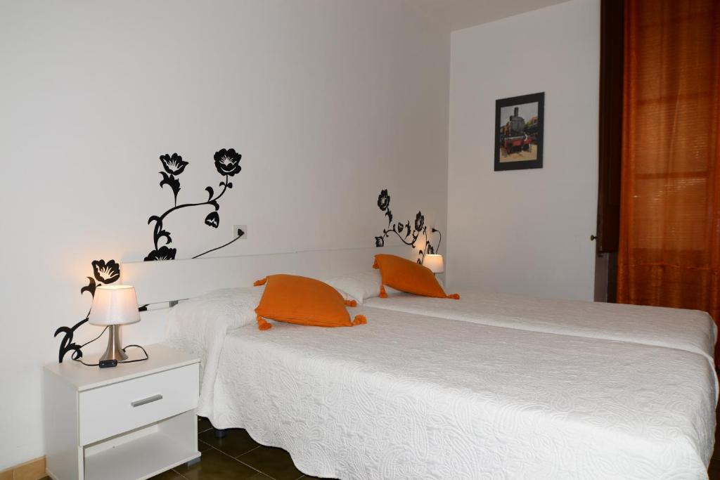 赫罗纳博拉斯酒店的卧室配有带橙色枕头的白色床