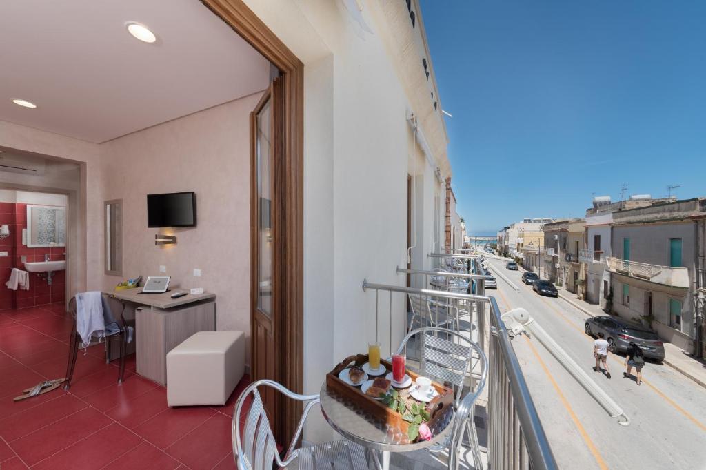 圣维托罗卡波Hotel Biancolilla的客房设有阳台,餐桌上摆放着蛋糕