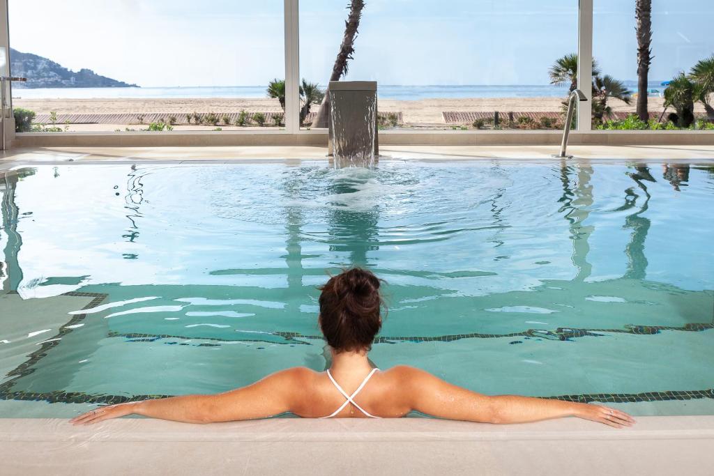 罗萨斯Hotel Montecarlo Spa & Wellness的躺在游泳池中看海洋的女人