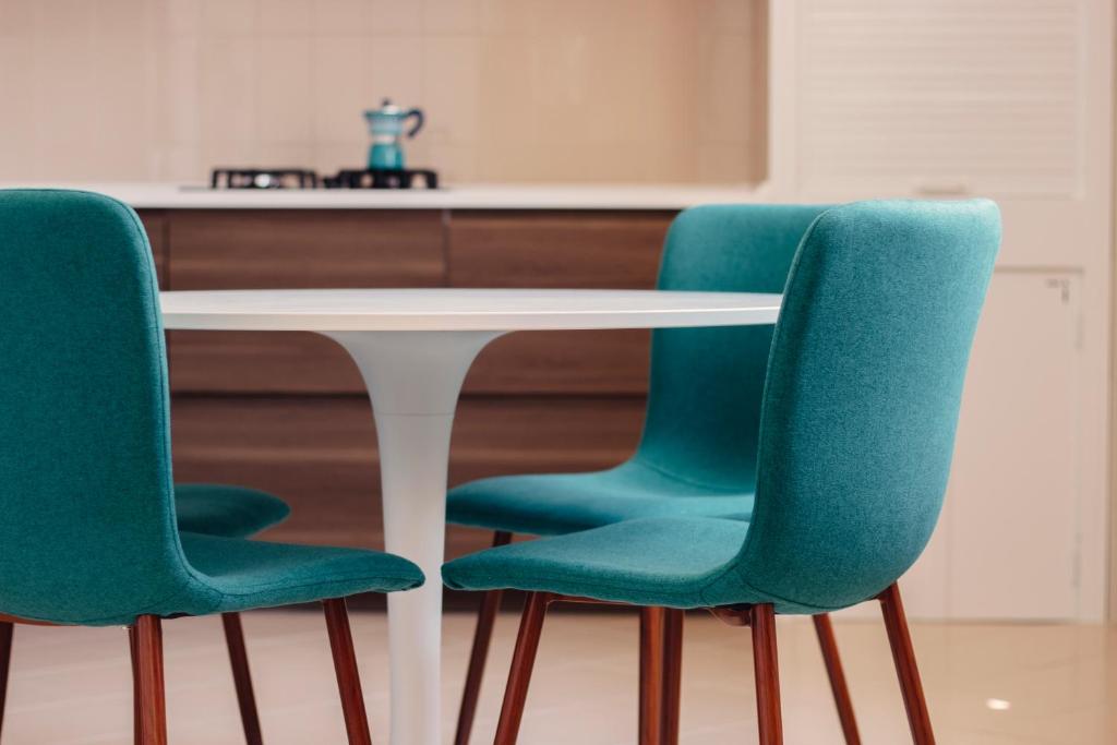 孔韦尔萨诺Alchimia Apartment的厨房里白色桌子周围摆放着三把绿色椅子