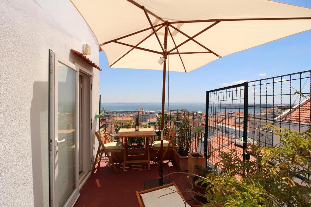 里斯本Estrela Penthouse - Amazing Views的阳台配有桌子和雨伞。