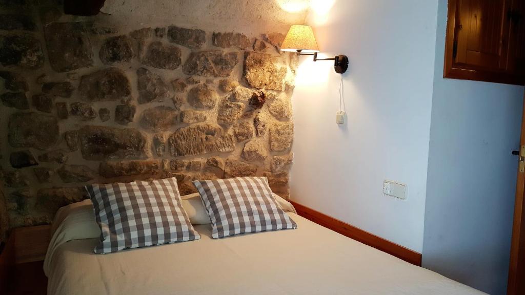 奥尔塔-德圣胡安Casa Templers的石墙间配有一张带两个枕头的床