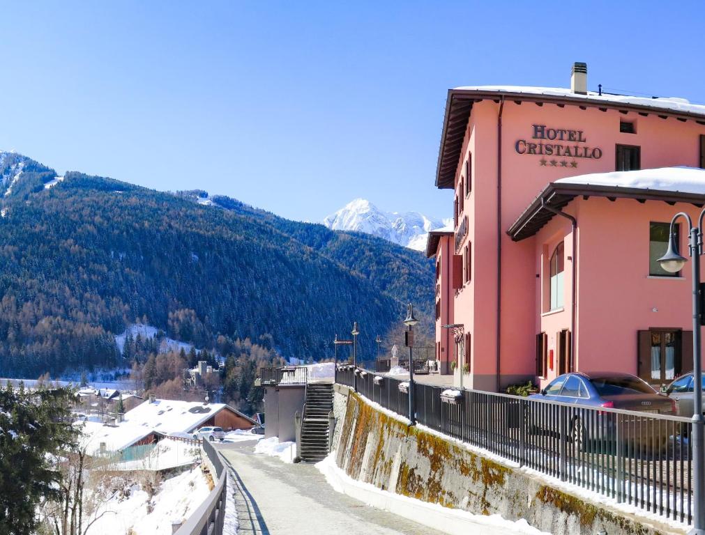 蓬泰迪莱尼奥Hotel Garni Cristallo的山中一座小镇,有一座粉红色的建筑