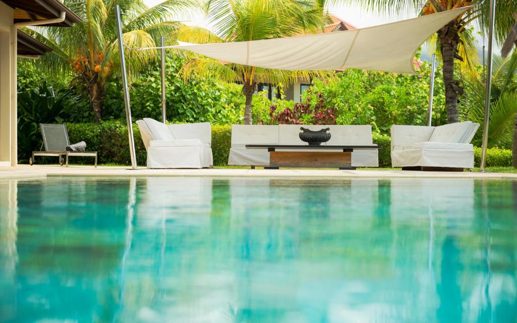 伊甸岛Eden Island Luxury Villa 235 by White Dolphin LLC的一个带椅子和桌子的游泳池以及一把遮阳伞