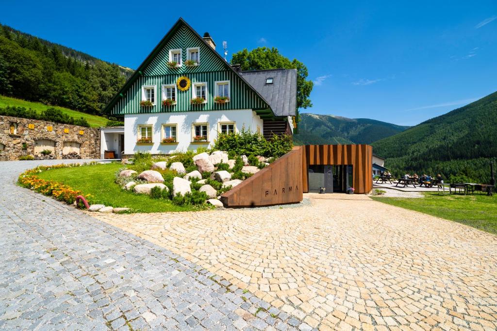 什平德莱鲁夫姆林Pension Slunečnice & Restaurace Farma的一座带绿色屋顶和砖瓦车道的房子