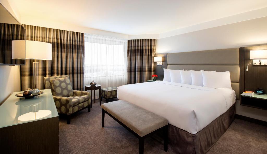 萨斯卡通萨斯卡通会议中心酒店的酒店客房带一张大床和一把椅子