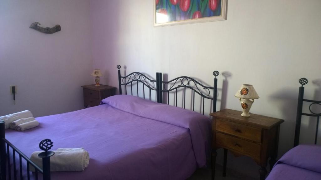 马利耶萨兰托度假住宿加早餐旅馆的一间卧室配有一张带紫色床单的床和梳妆台