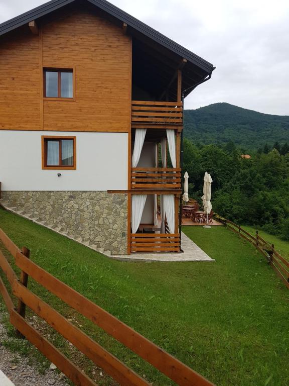 塞里特雷尼科B&B Apartments Burić Plitvice Lakes的绿色田野旁的带围栏的建筑