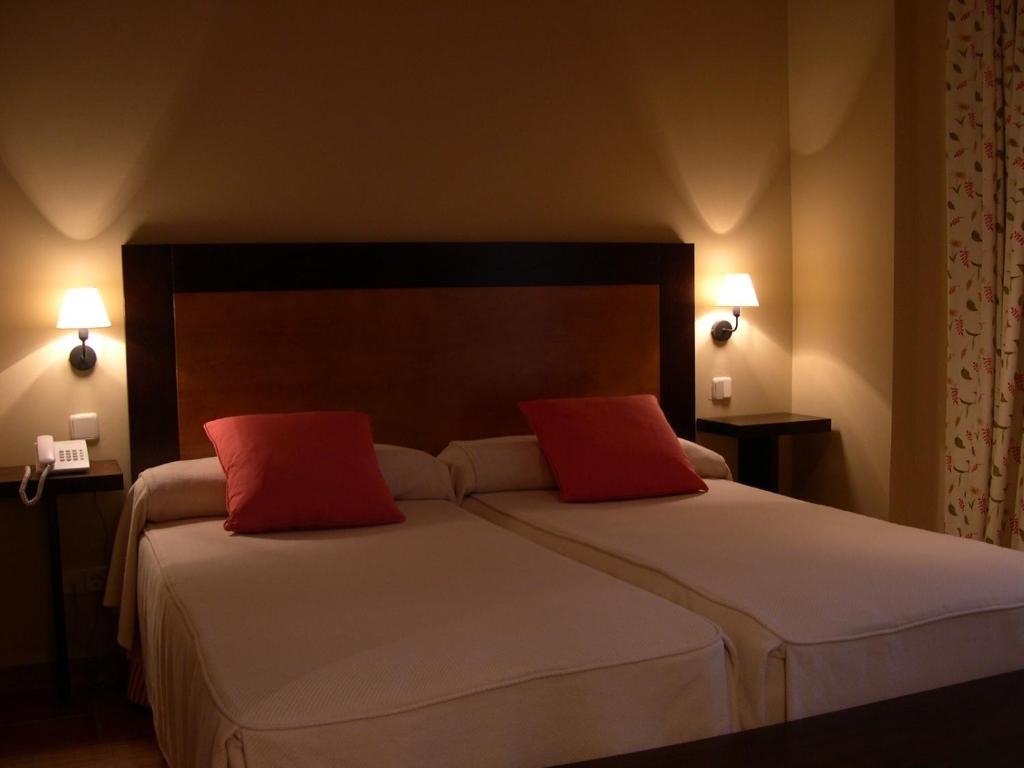 ValsainHotel Rural El Jardin de la Hilaria的一间卧室配有一张大床和两个红色枕头