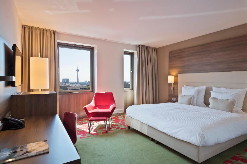 杜塞尔多夫杜塞尔多夫美利亚酒店的酒店客房,配有一张床和一张红色椅子