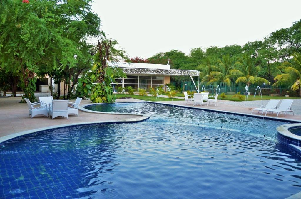 莫索罗魏里奥斯特酒店的一个带白色椅子的游泳池,一个度假村